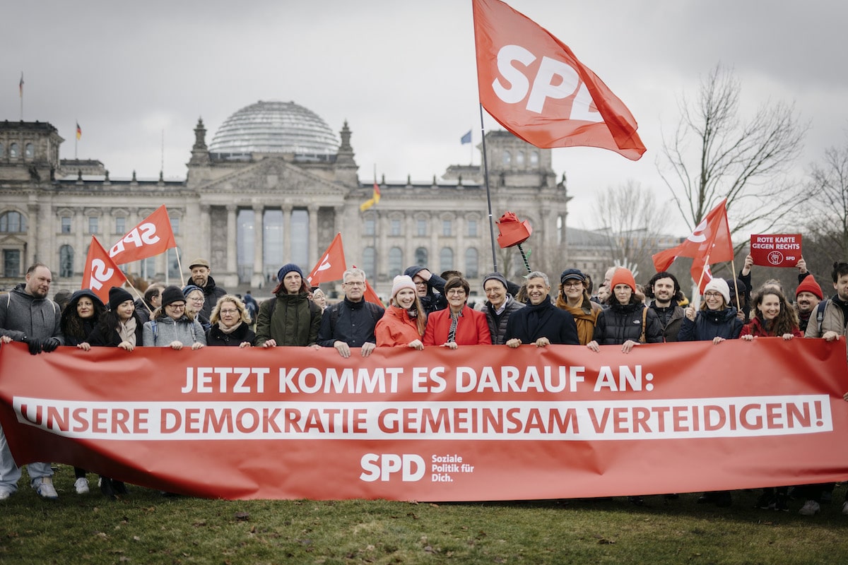 Foto: SPD-Mitglieder halten ein Banner "Unsere Demokratie gemeinsam verteidigen!" vor dem Reichstagsgebäude in Berlin