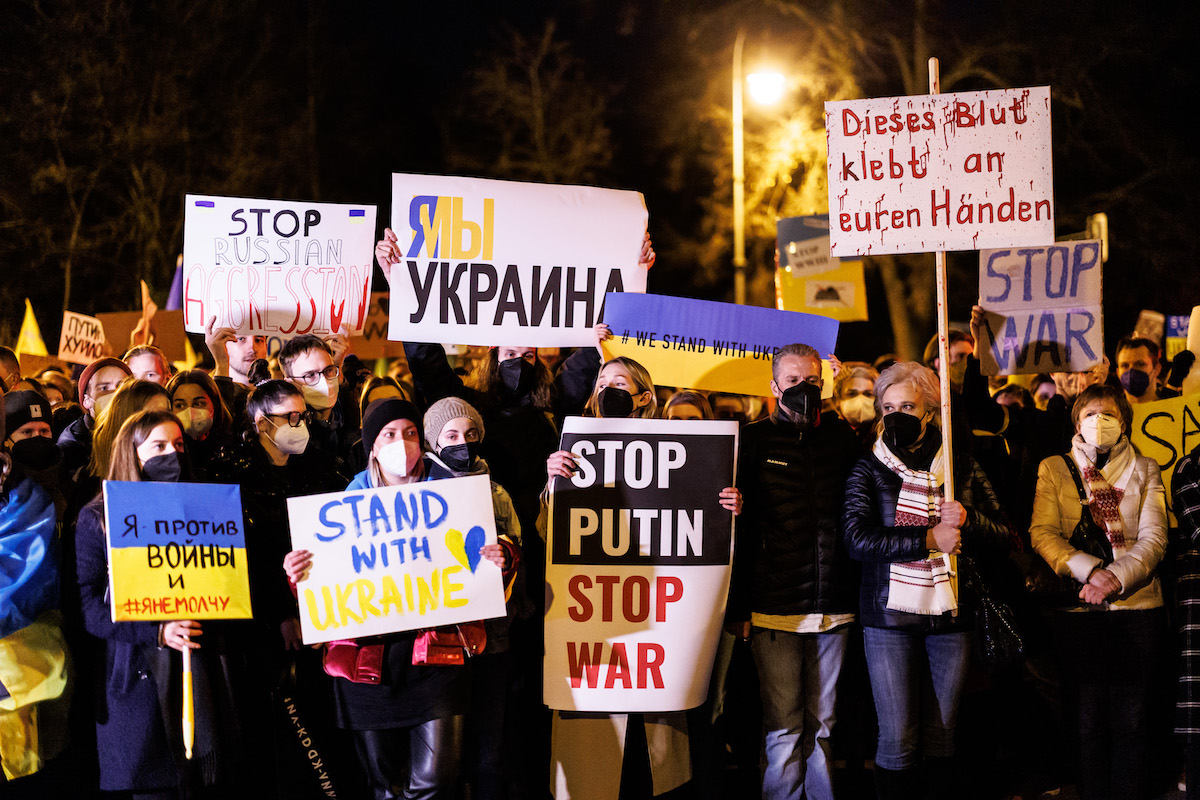 Foto: Teilnehmer einer Demonstration gegen den Angriff Russlands auf die Ukraine protestieren mit Schildern und Fahnen am russischen Generalkonsulat in München