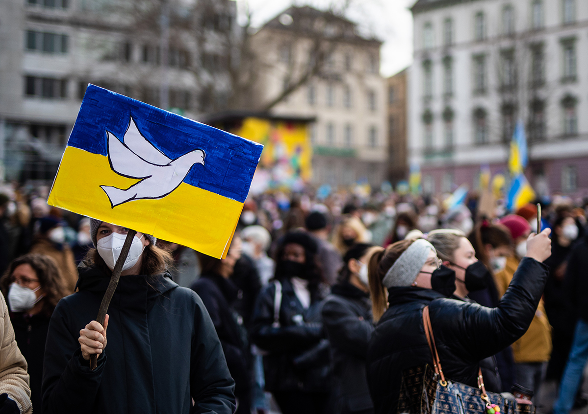 Foto: Demonstration in Stuttart mit Hochhalteschild, das die ukrainische Flagge mit einer Friedenstaube zeigt