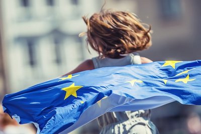 Foto: Mädchen läuft mit Europafahne durch eine Straße