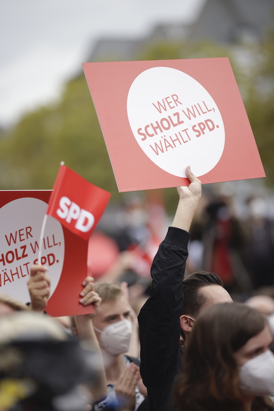 Foto: Junger Mann hält Schild "Wer Scholz will, wählt SPD." hoch