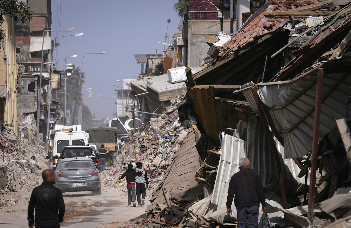 Foto: Anwohner gehen auf einer Straße in Antakya an den Trümmern von Gebäuden vorbei.