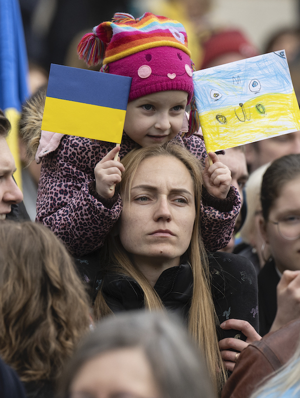 Foto: Mädchen hält ukrainische Fahne und Bild in ukrainischen Nationalfarben