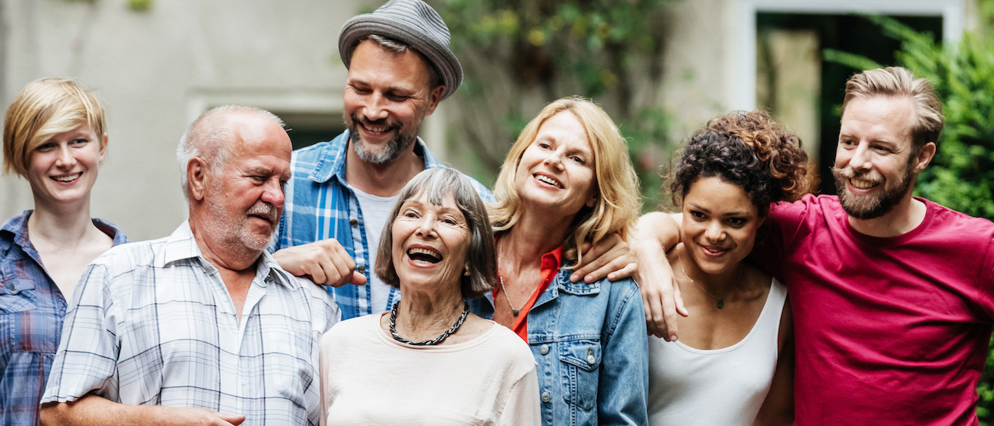 getty Foto: Menschen stehen in einer Gruppe zusammen und lachen miteinander