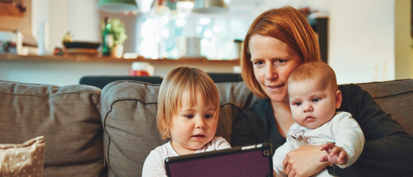 Foto: Mutter und Kleinkinder sitzen in einer Wohnung auf einem Sofa