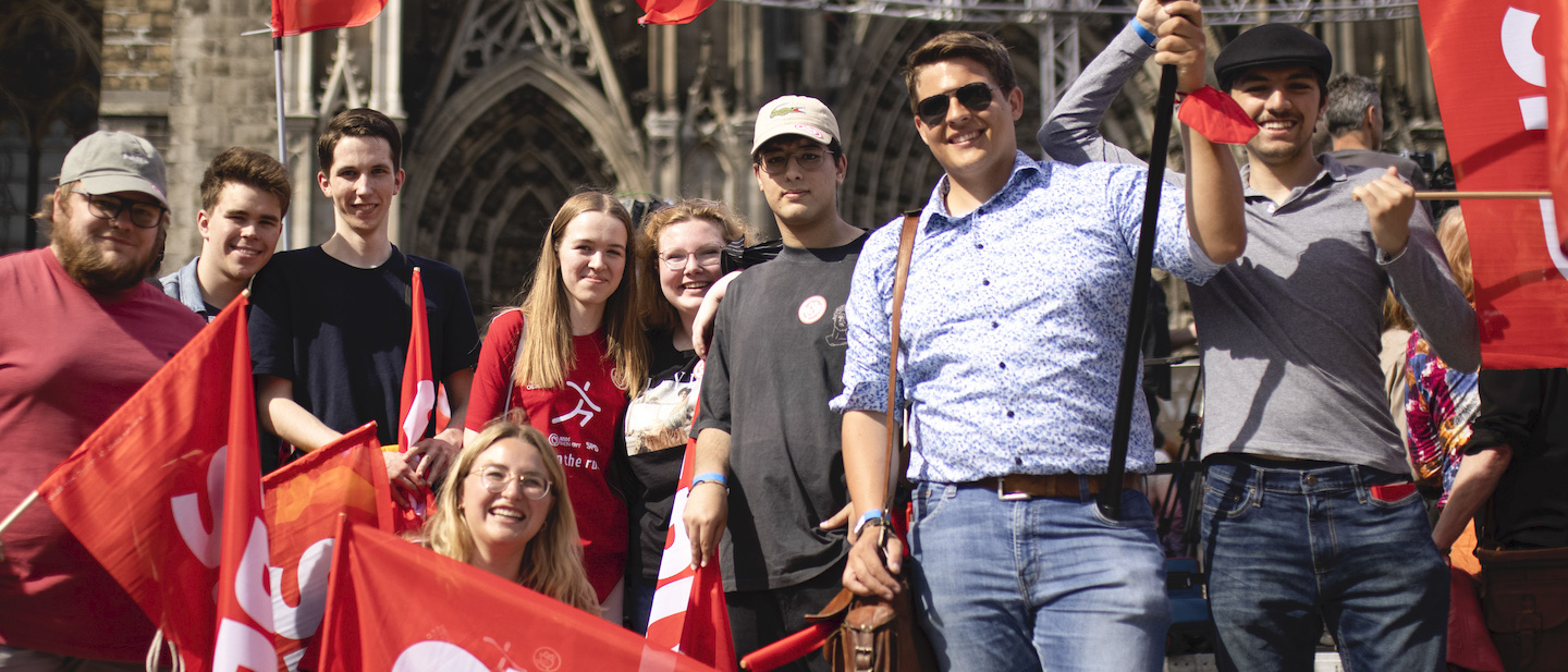 Foto: SPD-Mitglieder stehen Fahnen schwenkend vor dem Kölner Dom