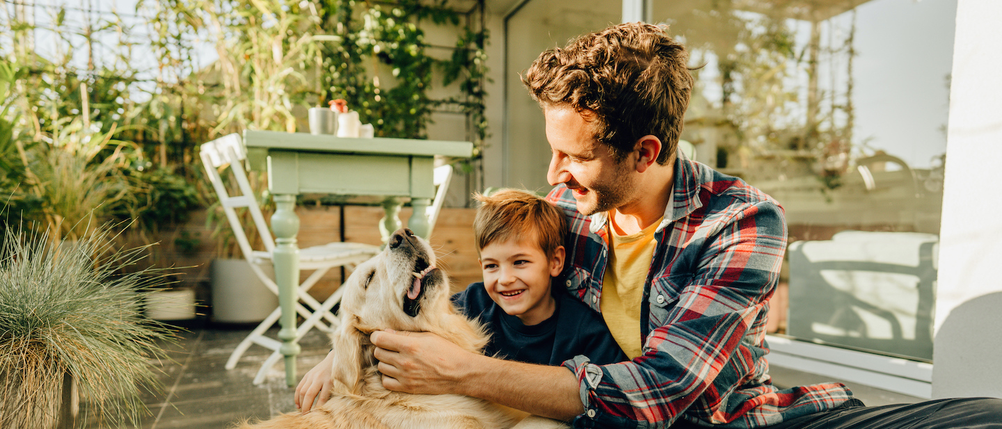 Foto: Vater und Sohn spielen mit Hund auf Terasse