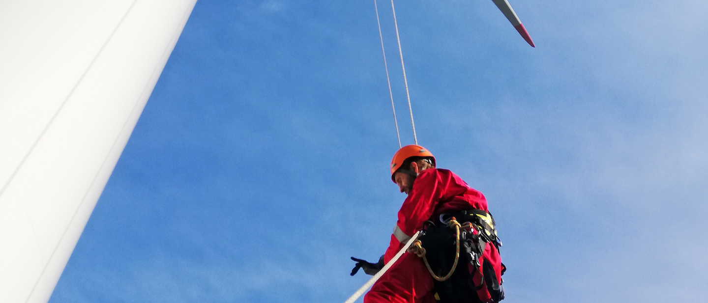 Foto: Industriekletterer hängt am Seil und arbeitet an Windkraftanlage