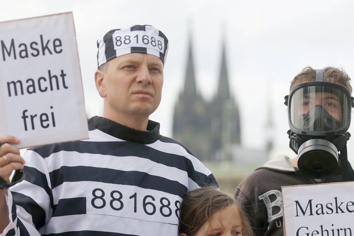 Foto: Mann hält bei Corona-Demonstration Schild mit dAufschrift "Maske macht frei" in die Höhe