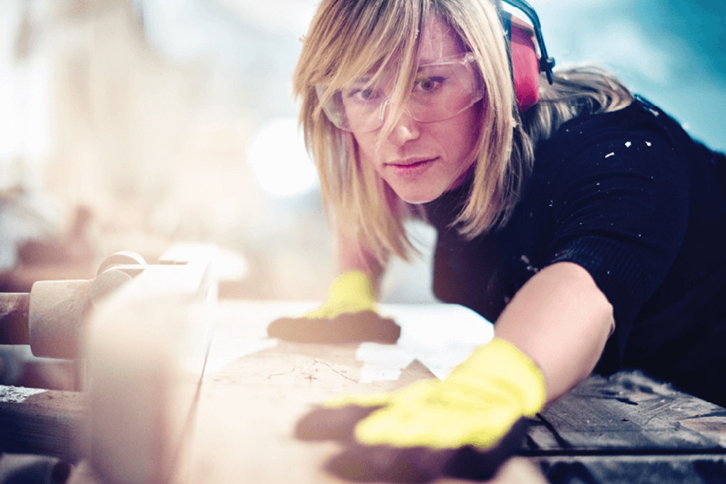 Foto: Handwerkerin arbeitet mit Gehörschutz