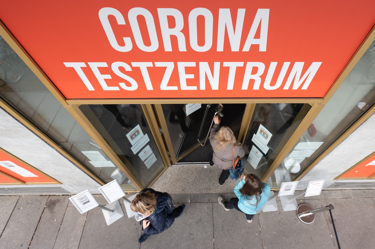 Foto: Passanten gehen in ein Corona-Testzentrum