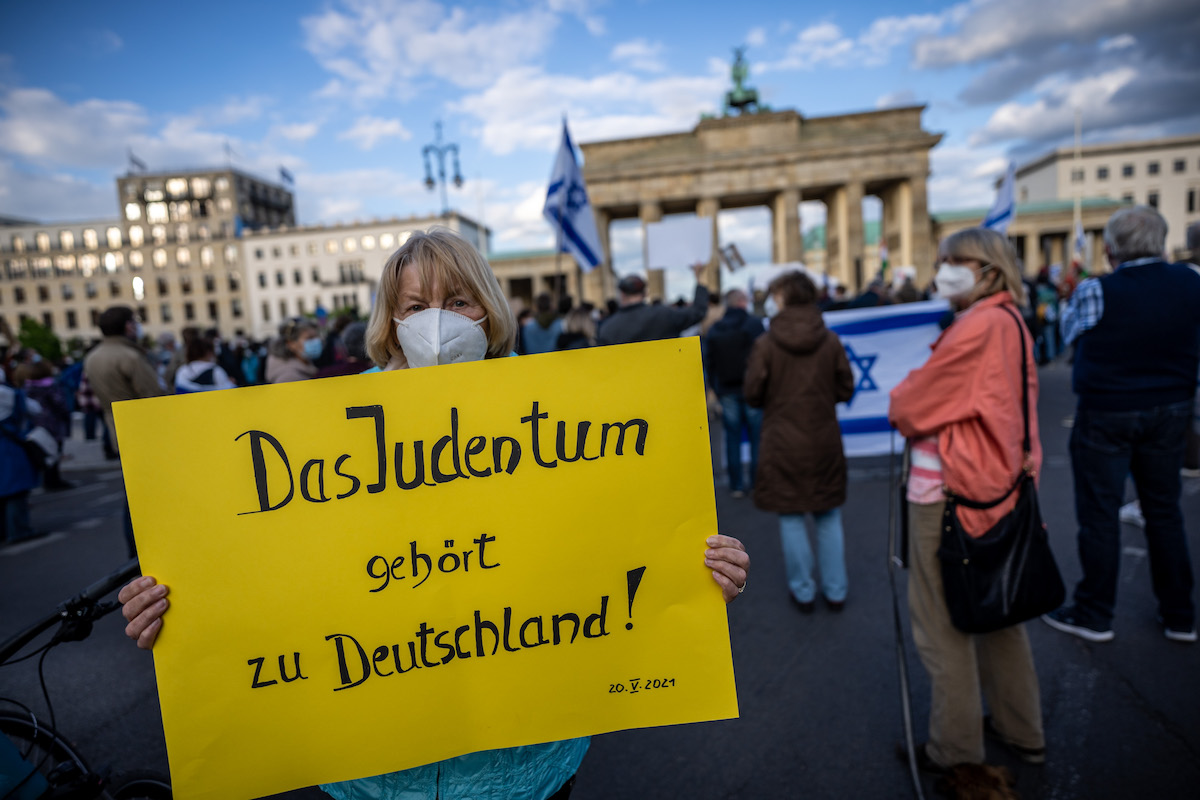 Foto: Demonstrantin hält Plakat mit der Aufschrift „Das Judenturm gehört zu Deutschland!“ vor dem Brandenburger Tor. 