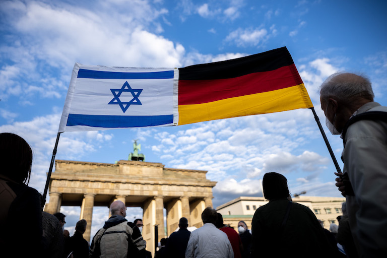 Foto: Teilnehmer an einer Demonstration zur Solidarität mit Israel stehen mit den Flaggen Israels und Deutschlands vor dem Brandenburger Tor. 