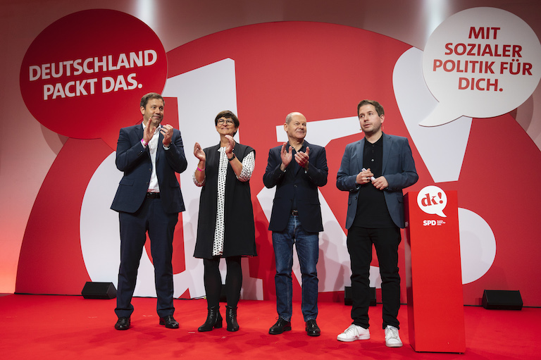 Foto: Lars Klingbeil (l-r), Saskia Esken, Olaf Scholz und Kevin Kühnert stehen zusammen auf der Bühne.