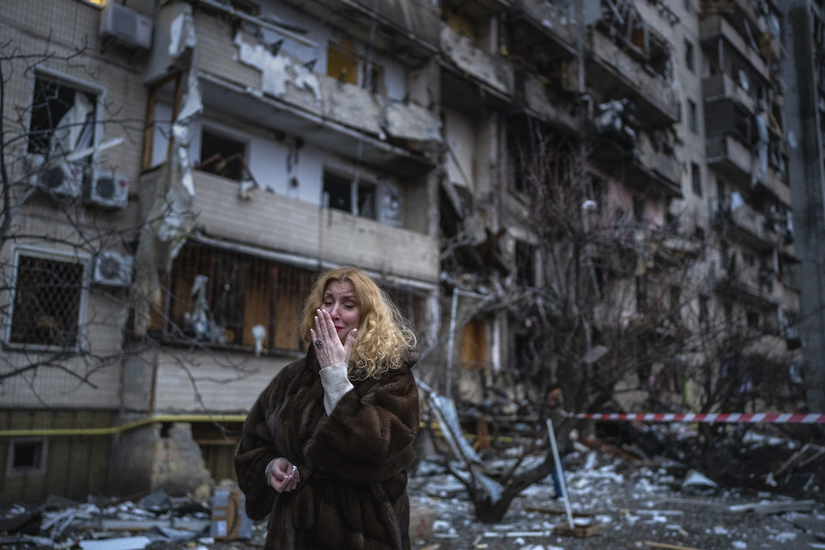 Foto: Frau steht fassungslos neben einem Haus, das bei einem russischen Raketenangriff in Kiew zerstört wurde.