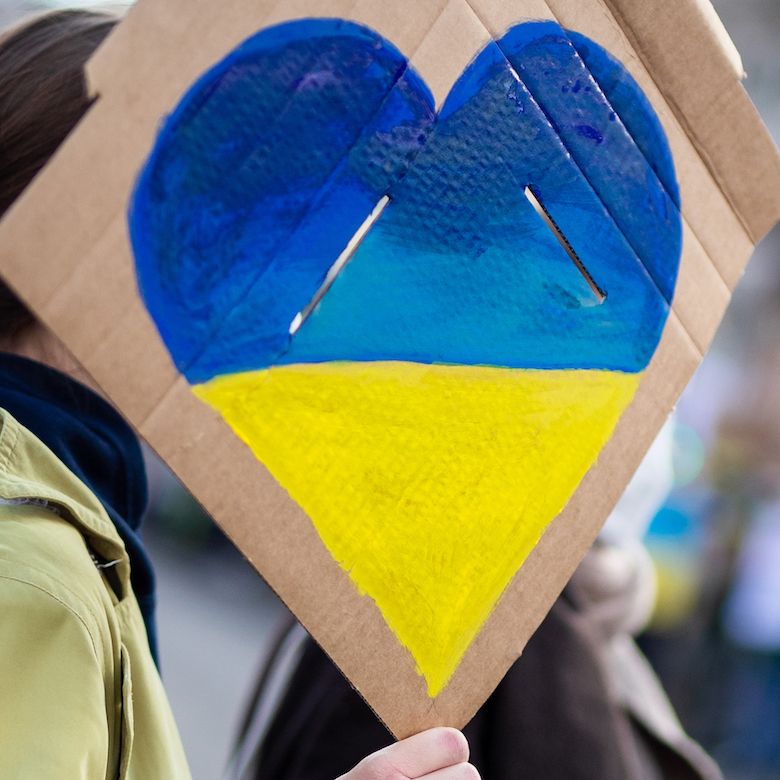 Foto: Frau hält ein Schild mit einem Herz in den Farben der Ukraine in ihrer Hand