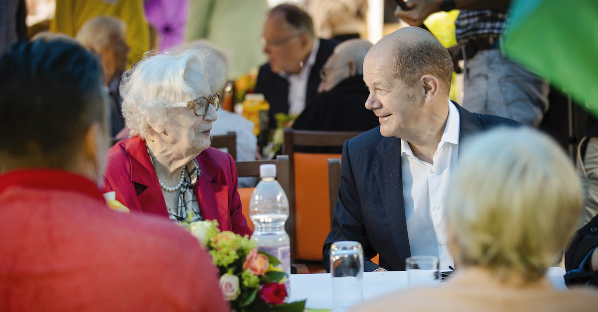 Foto: Olaf Scholz unterhält sich am Tisch mit einer Seniorin