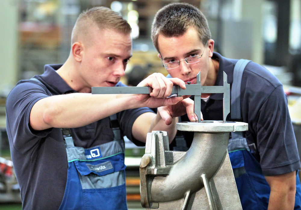 Ein Lehrling und ein Geselle hantieren mit einem Messschieber. (Foto: dpa) 