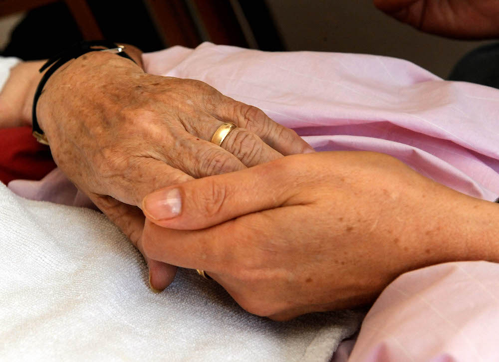 Die Hand einer kranken Frau wird von einer Pflegerin gehalten. Wenn todkranke Menschen nicht im Krankenhaus sterben wollen, muss rechtzeitig ein Platz im Hospiz oder eine gute Betreuung daheim organisiert werden. (Foto: dpa)