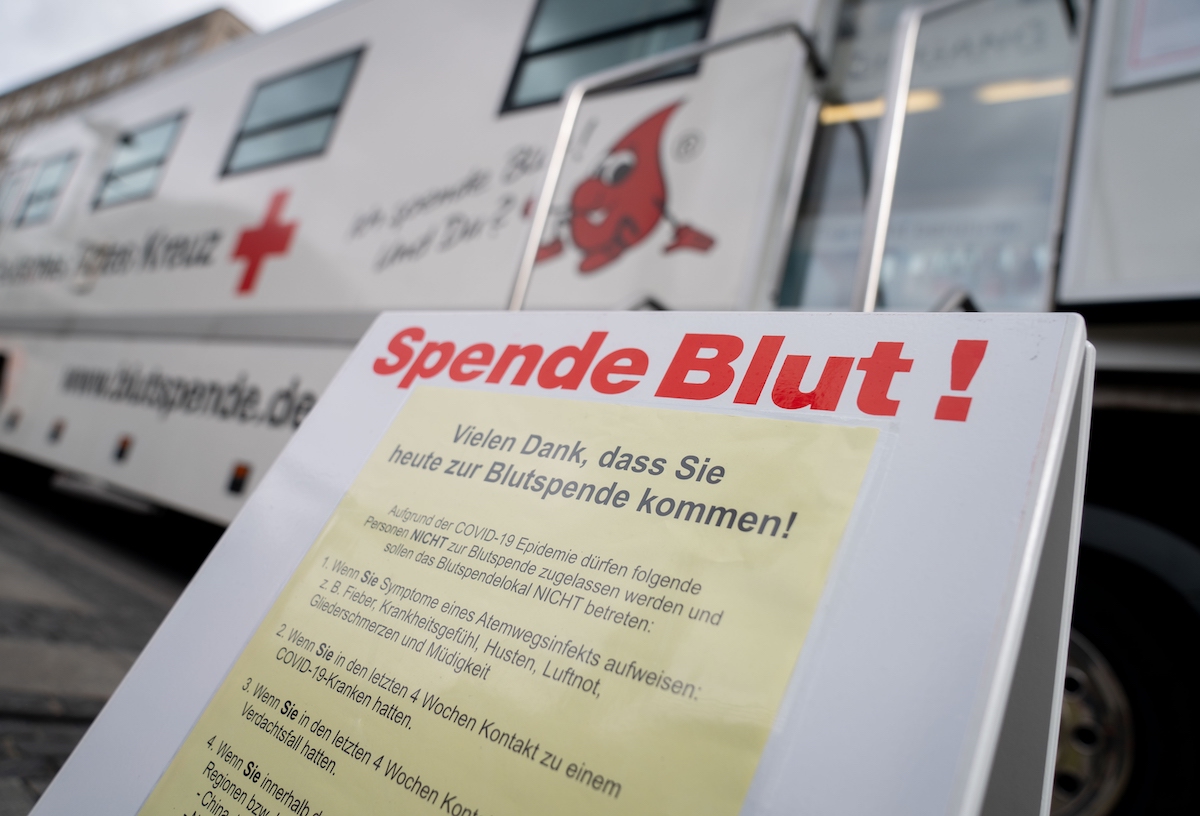 Foto: "Spende Blut" steht auf einem Plakat vor einem Blutspende-Bus