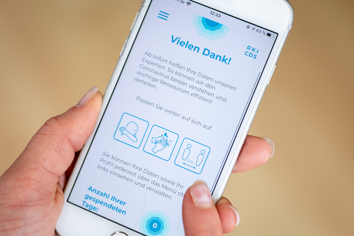 Foto: Nutzerin hält Handy mit Coronavirus-App in den Händen