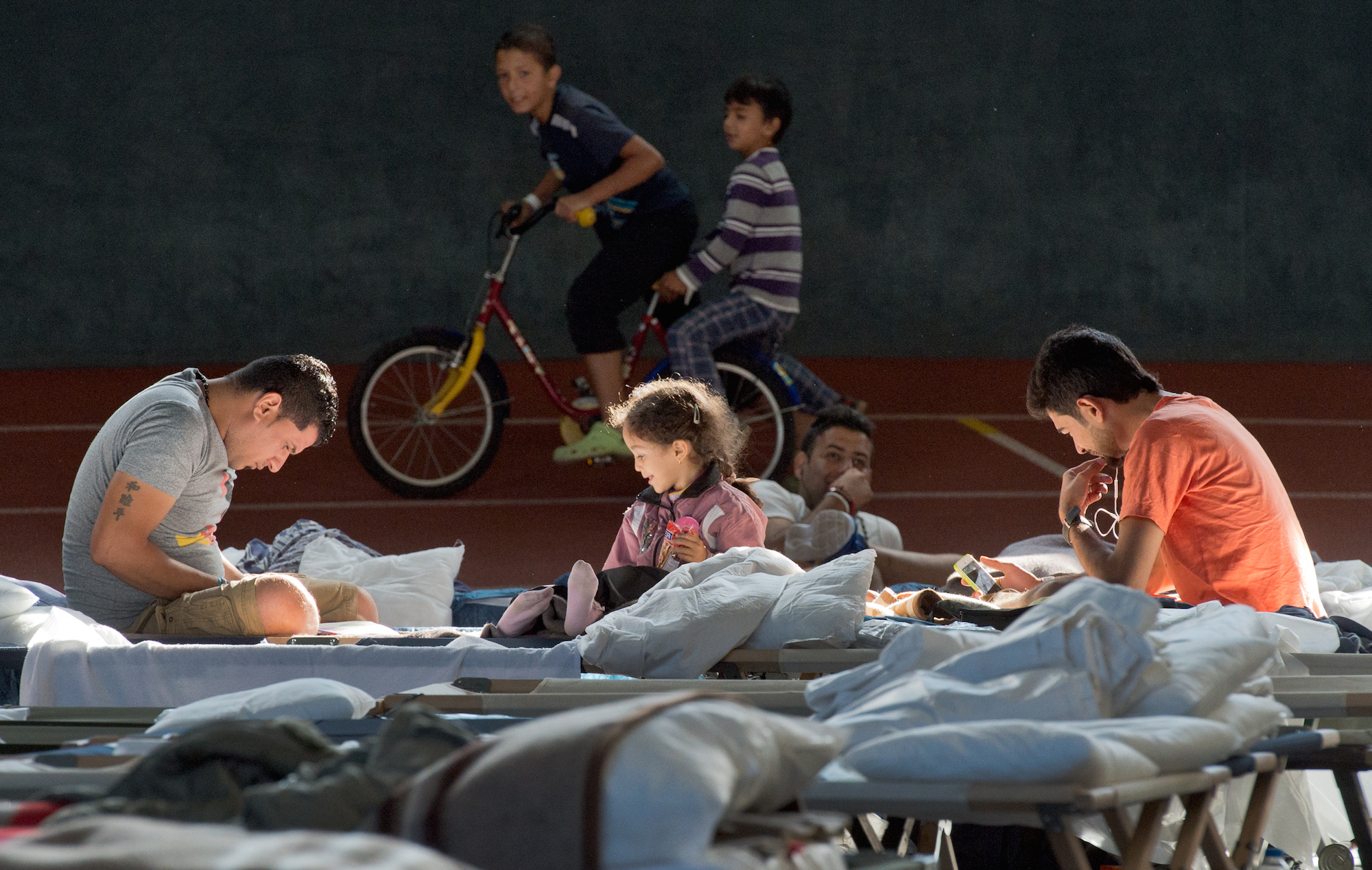 Foto: Auf ihren Feldbetten sitzen Flüchtlinge in der August Schärttner Turnhalle in Hanau (Hessen).