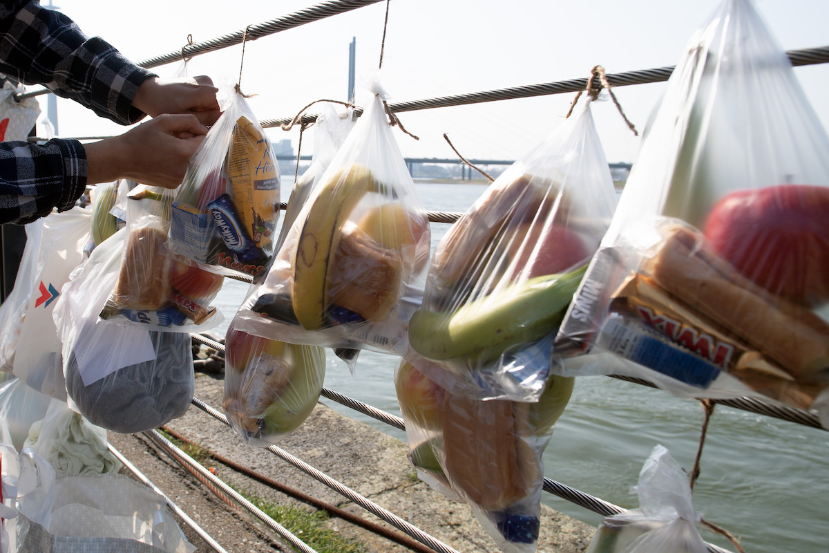 Foto: Helfer bindet Beutel mit Lebensmitteln an Gabenzaun