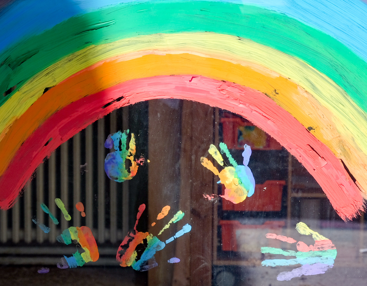 Foto: Kinderhände und ein Regenbogen sind an einer Kita zu sehen