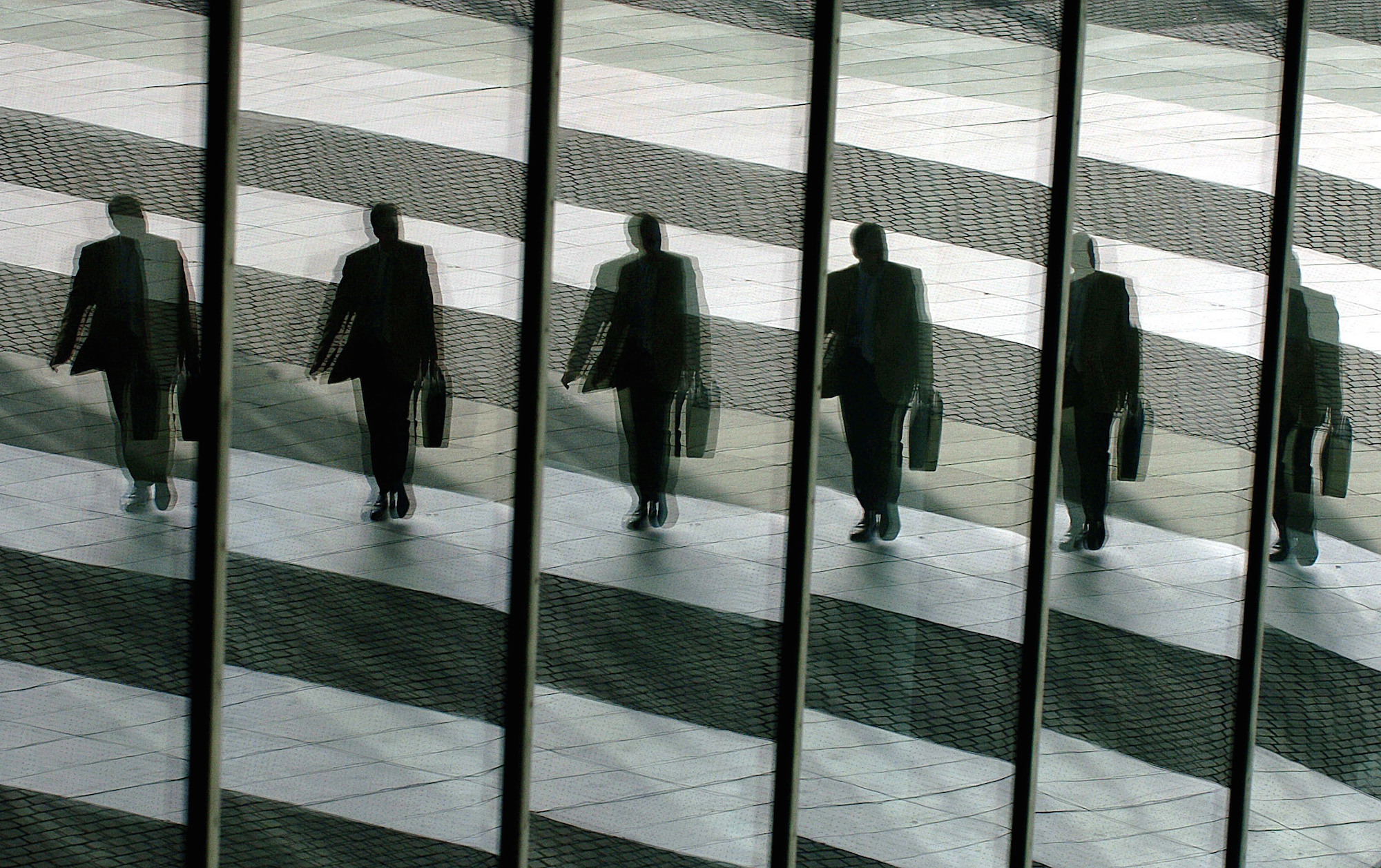 Foto: Ein Mann mit Aktentasche geht in Bonn ins Büro und spiegelt sich dabei in den Glasscheiben der Post-Towers (Archivfoto, Illustration zum Thema Manager)