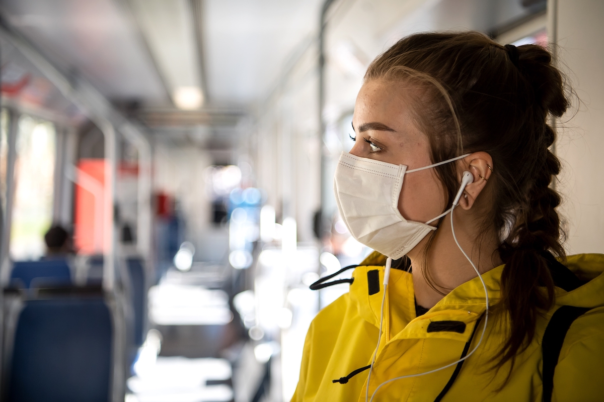 Foto: Eine Frau mit einer Schutzmaske steht in einer Straßenbahn.