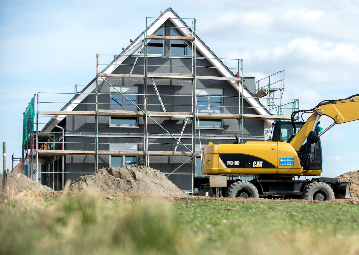 Foto: Ein eingerüsteter Rohbau eines Einfamilienhauses steht in einem Neubaugebiet. 