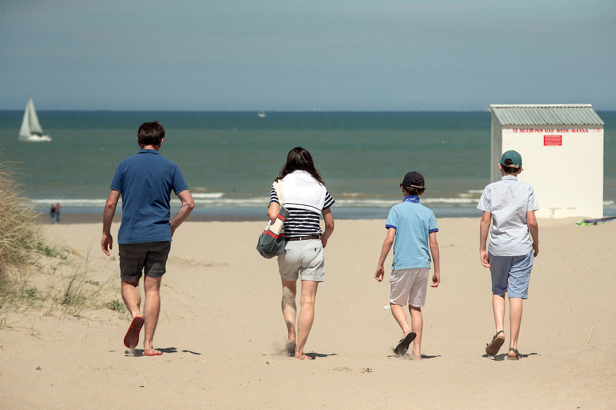 Foto: Menschen genießen einen Strandspaziergang in der Sonne. 