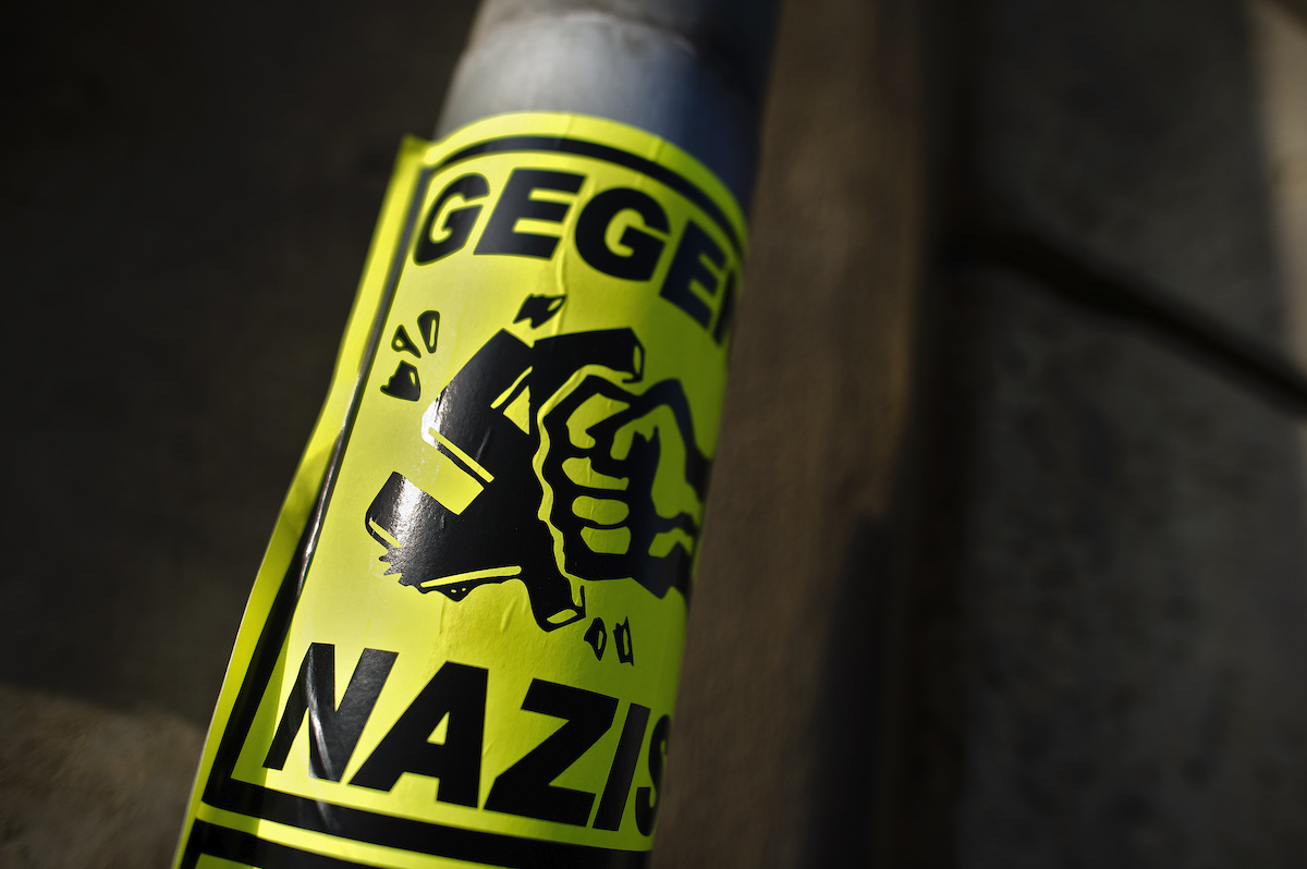 Foto: Ein Aufkleber „Gegen Nazis“ klebt an einem Straßenschild.