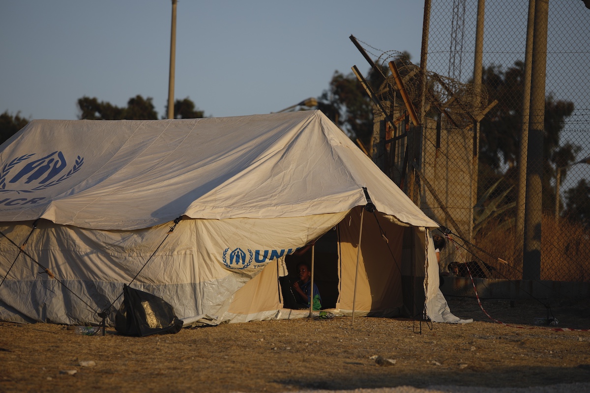 Foto: Ein Junge sitzt in einem Zelteingang in einem provisorisches Zeltlager für geflüchtete Menschen in der Nähe von Mytilini.