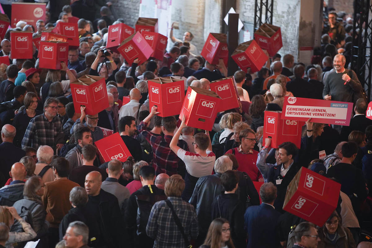 Foto: Teilnehmer tragen Sitzhocker mit SPD-Logo beim SPD-Debattencamp durch die Menge.