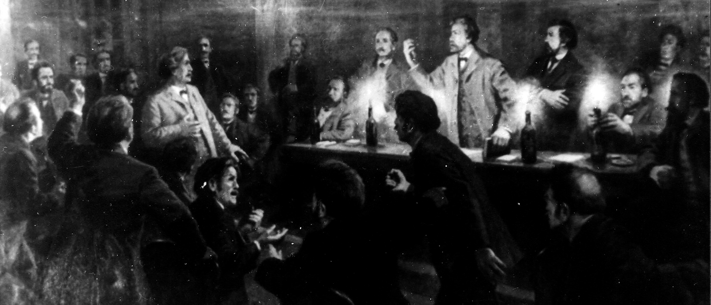 Foto: Adolf Hepner, Wilhelm Liebknecht (mit erhobenem Arm) und August Bebel diskutieren auf dem Podium beim 6. Vereinstag des Verbandes der deutschen Arbeitervereine in Eisenach, 1869