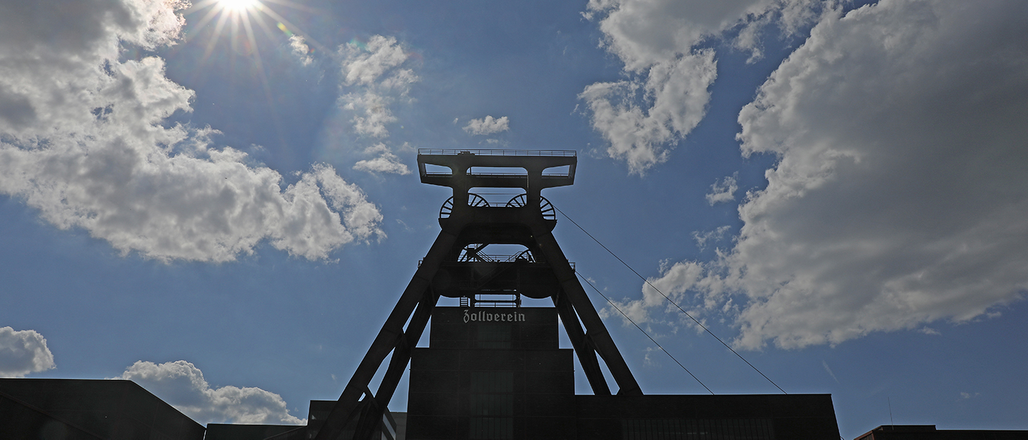 Foto: 17.06.2019, Nordrhein-Westfalen, Essen: Die Sonne scheint hinter dem Förderturm der Zeche Zollverein. Gemeinsam mit der unmittelbar benachbarten Kokerei Zollverein gehört die Zeche seit 2001 zum Welterbe der UNESCO. 