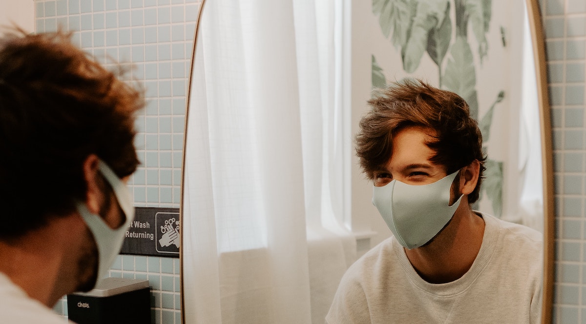 Foto: Mann mit Atemschutzmaske wäscht sich vor Spiegel im Bad die Hände