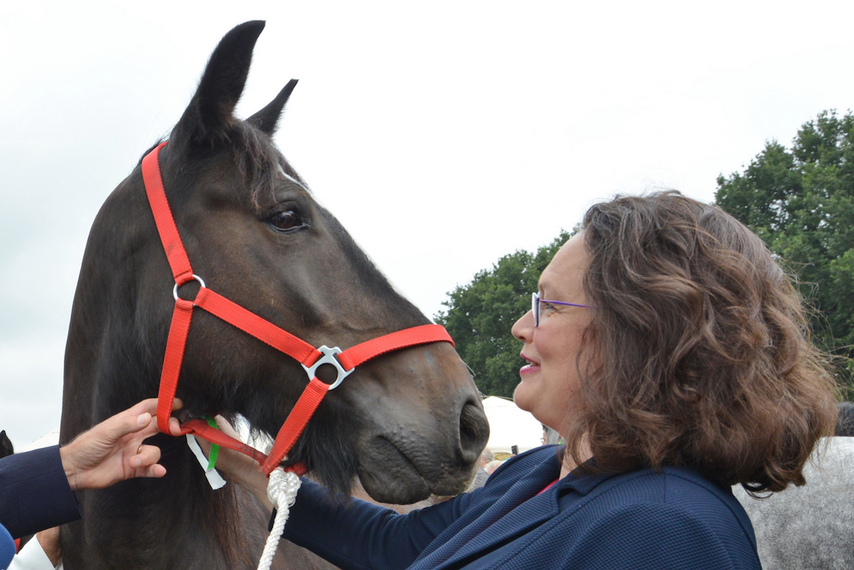 Foto: Andrea Nahles steht neben einem Pferd.