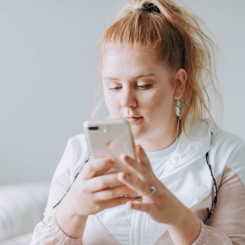Foto: Junge Frau liest auf Mobiltelefon