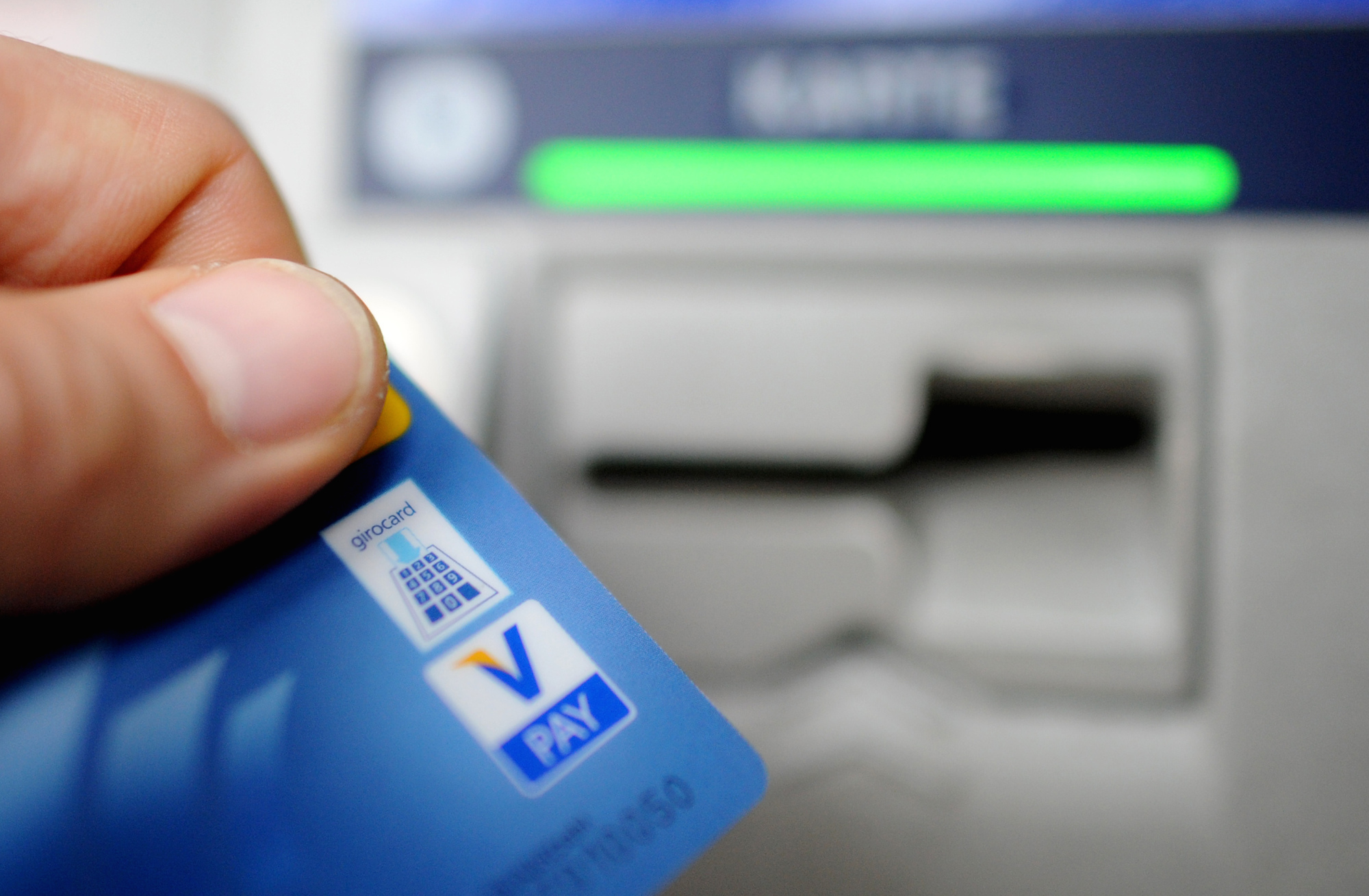 Foto: Bankkunde hebt mit seiner Girokarte Bargeld vom Geldautomaten ab. 