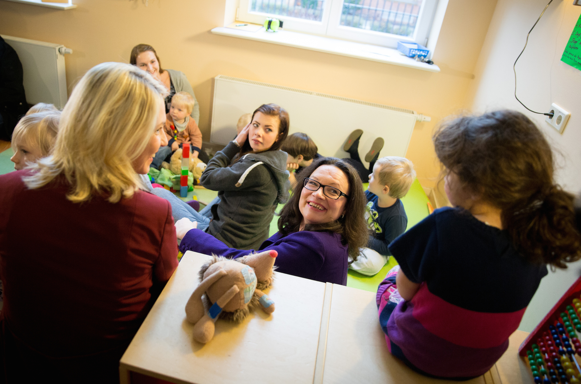 Manuela Schwesig (links) und Andrea Nahles sitzen in Berlin in einer Kindertagesstätte mit Kindern und Erzieherinnen zusammen.