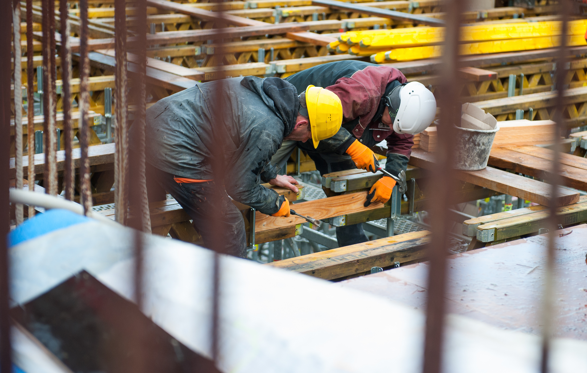 Foto: Bauarbeiter sind auf einer Baustelle für ein Gebäude beschäftigt.