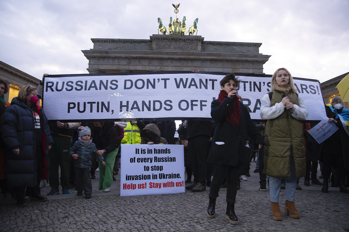 Foto: Menschen nehmen mit Plakaten mit der Aufschrift „Russians don´t want Putin´s wars! Putin, Hands off Ukraine!“ an einer Demonstration gegen den Krieg in der Ukraine vor dem Brandenburger Tor teil.