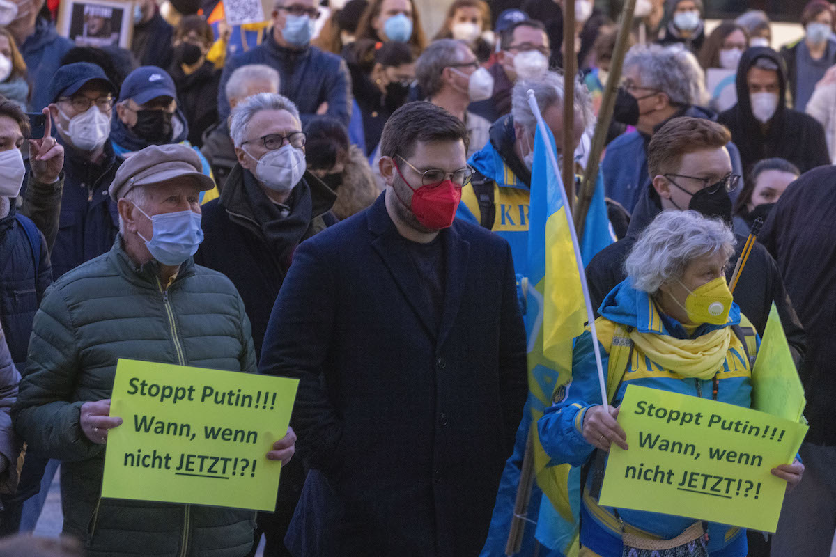 Foto: Menschen stehen mit Kerzen und Plakaten auf denen „Stoppt Putin!!! Wann, wenn nicht jetzt!?!“ bei der Demonstration in Mainz