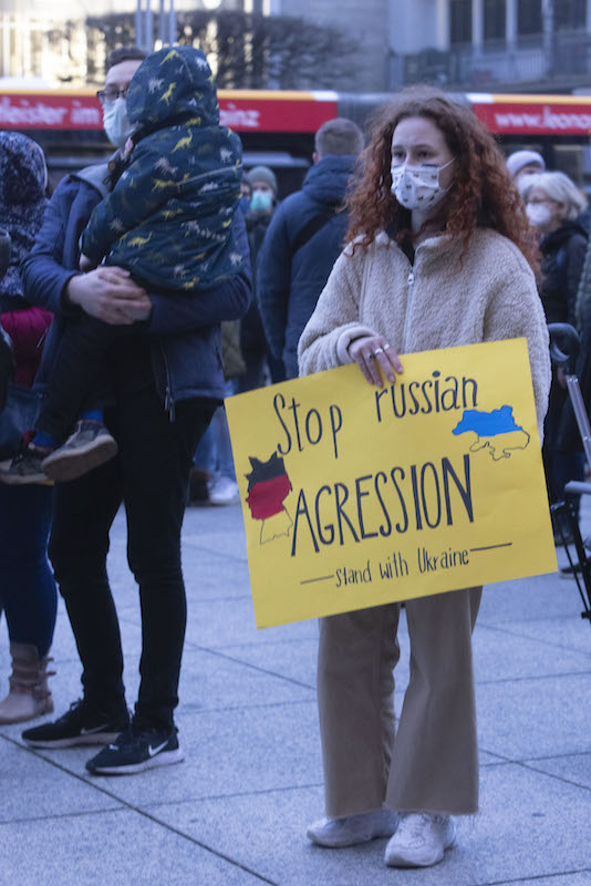 Foto: Eine Frau steht mit einem Plakat „Stop russian agression, stand with Ukraine“ bei der Demonstration in Mainz