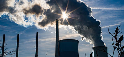Foto: Die Foto: Sonne strahlt durch eine Dampfwolke, die ein Kohlekraftwerk ausstößt. 
