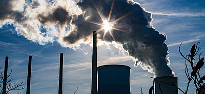 Foto: Die Foto: Sonne strahlt durch eine Dampfwolke, die ein Kohlekraftwerk ausstößt.