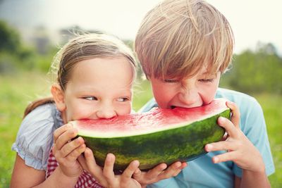 Foto: Zwei Kinder beißen in ein Melonenstück