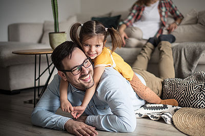 Foto: Tochter umarmt Vater auf Teppich als Symbol für Thema Wohnen/Miete
